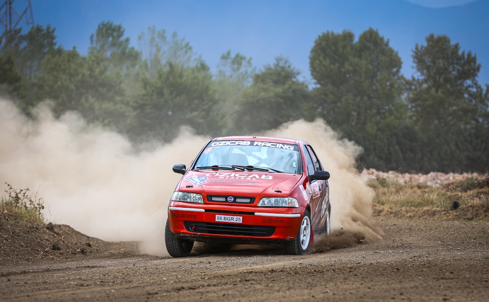 a red car driving down a dirt road