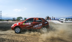 Crowd of enthusiastic fans cheering as Team 988’s car speeds past on a dirt track