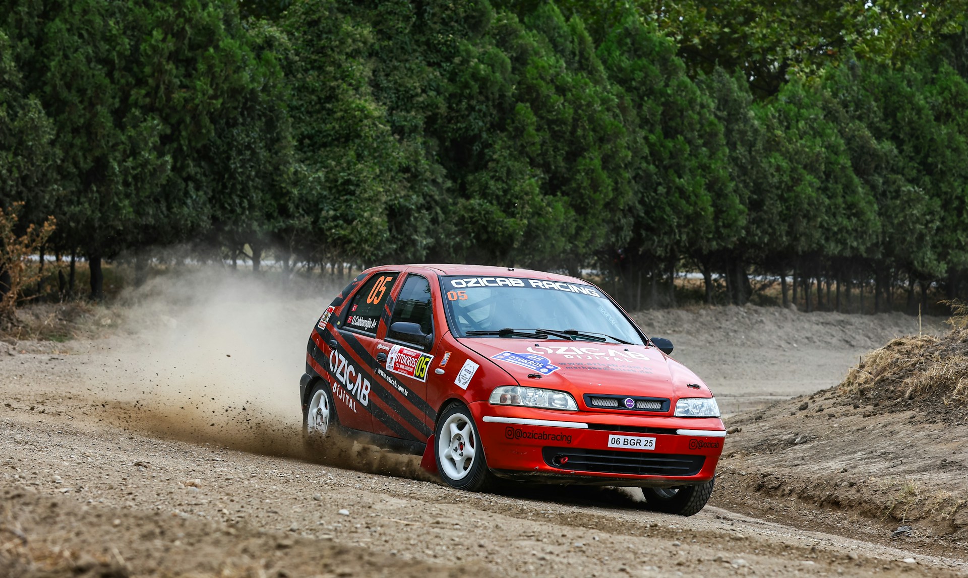 A dynamic motorsport race scene showing a speeding car kicking up dust on a sharp turn.