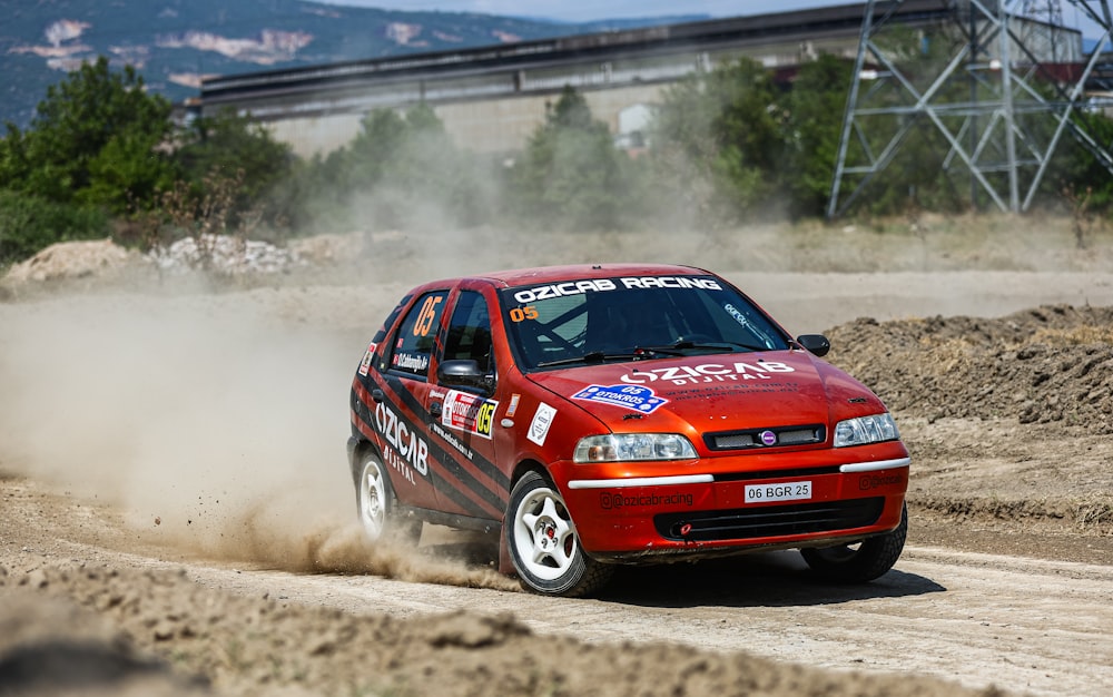 a red car driving down a dirt road