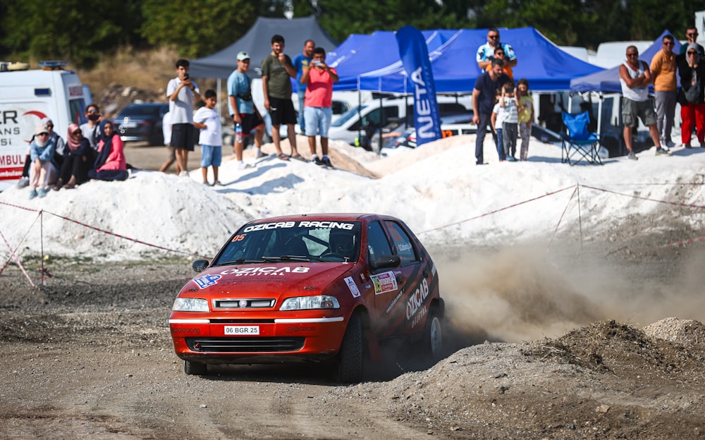 a red car driving down a dirt road