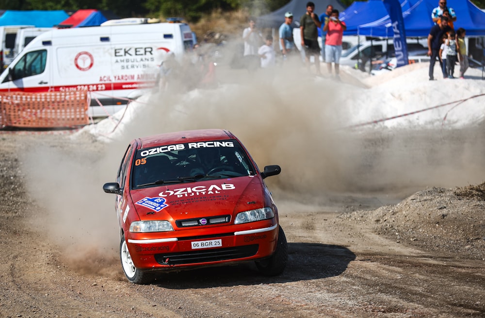 a red car driving down a dirt road