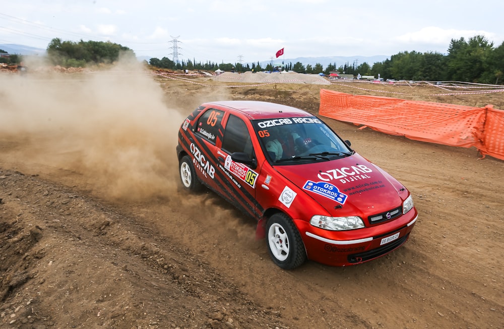 a red car driving down a dirt road