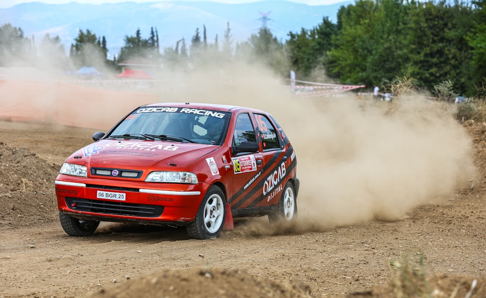 a red car driving down a dirt road