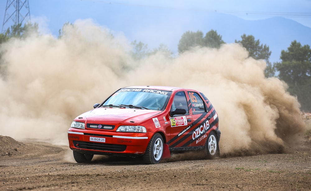 a red car driving down a dirt road