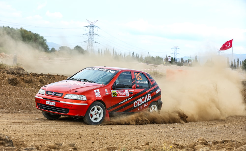 a red car driving down a dirt road