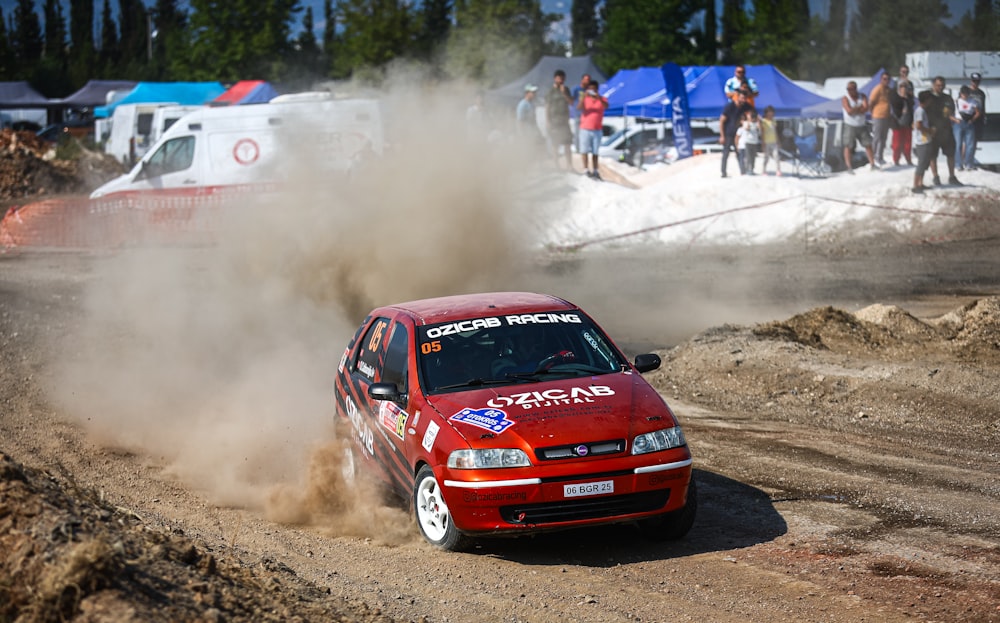 a red car driving down a dirt road