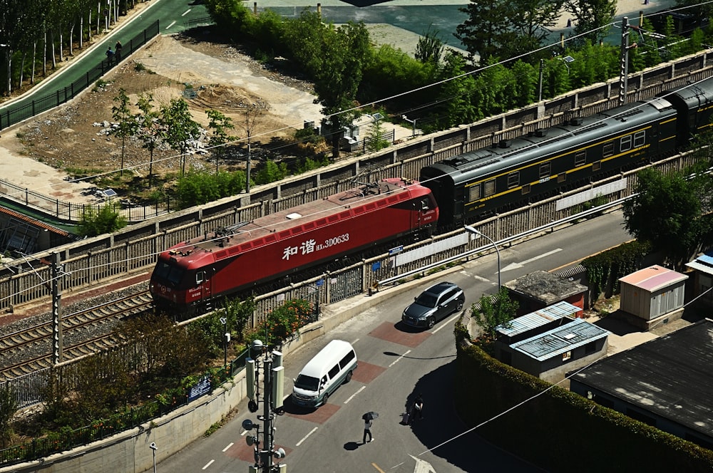 a red train traveling down train tracks next to a street