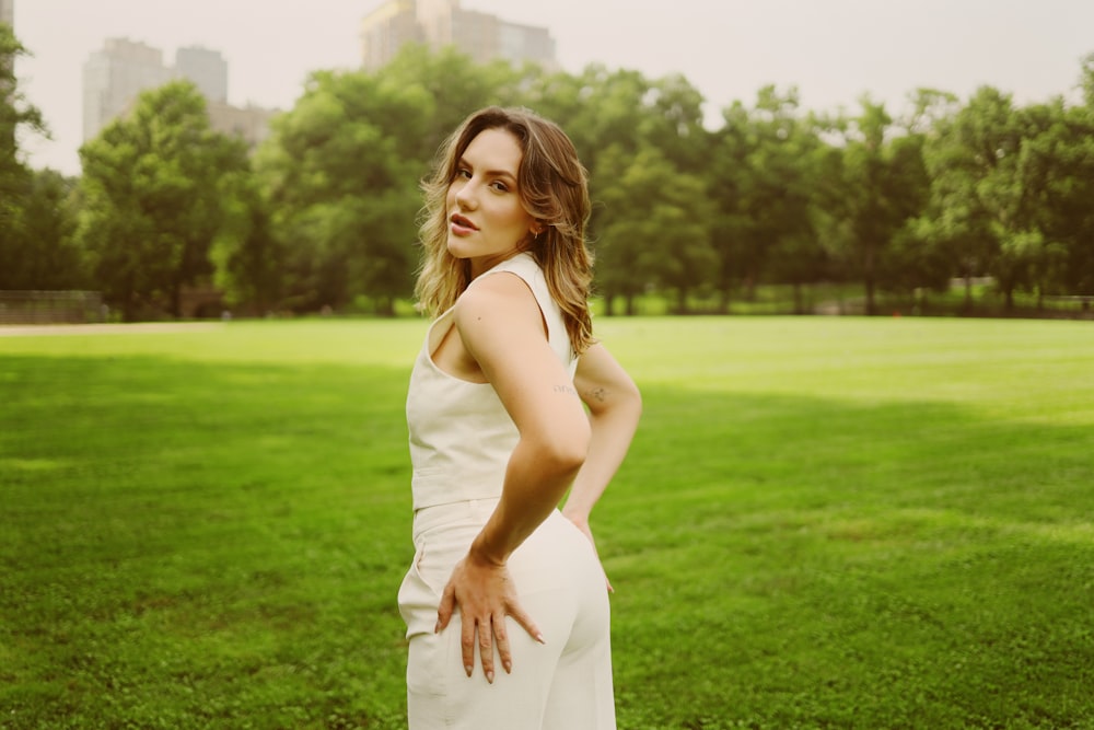 a woman standing in a field with her hands on her hips