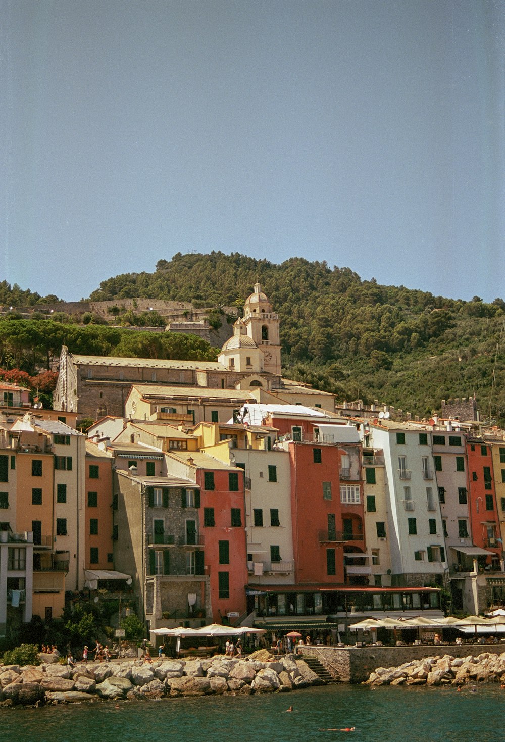 a group of buildings sitting on top of a hill next to a body of water