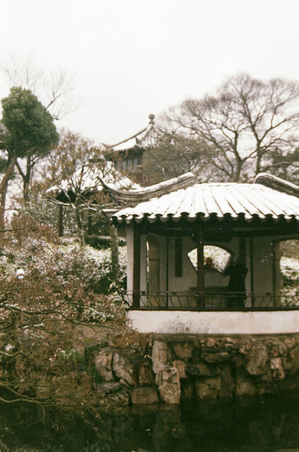 a gazebo sitting on top of a stone wall next to a forest