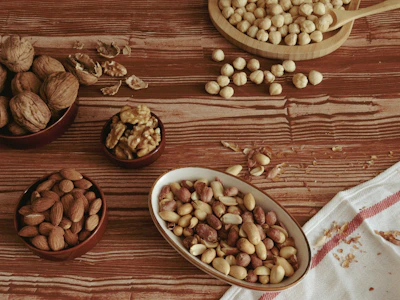 A rustic bowl filled with a variety of raw nuts including almonds, walnuts, and cashews on a wooden table.