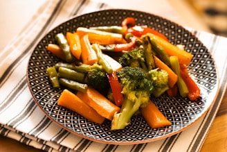 a plate of broccoli and carrots on a table