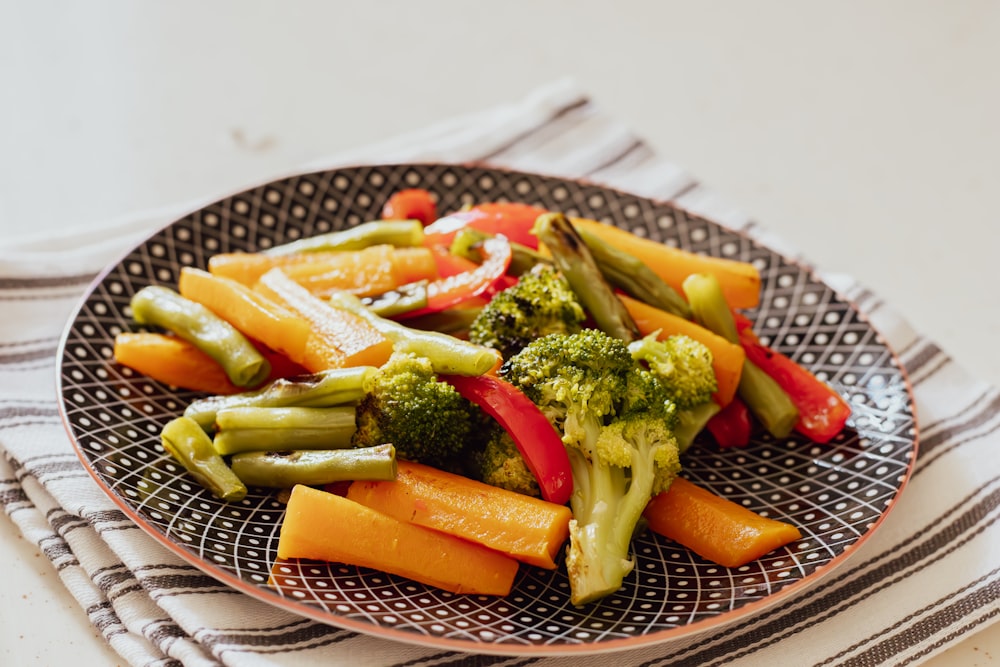 a plate of broccoli, carrots, and peppers