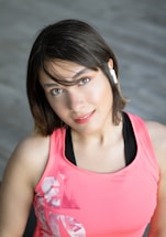 A friendly customer support representative wearing a headset with fitness gear in the background.