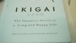 A close-up view of a book cover titled 'IKIGAI: The Japanese Secret to a Long and Happy Life' by Héctor García and Francesc Miralles. The cover is predominantly light blue with black and white text.