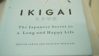 A close-up view of a book cover titled 'IKIGAI: The Japanese Secret to a Long and Happy Life' by Héctor García and Francesc Miralles. The cover is predominantly light blue with black and white text.