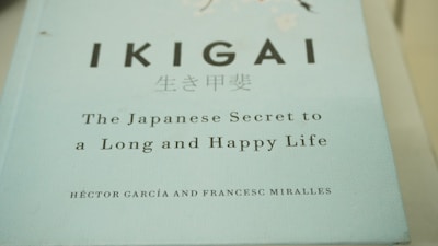 A close-up view of a book cover titled 'IKIGAI: The Japanese Secret to a Long and Happy Life' by Héctor García and Francesc Miralles. The cover is predominantly light blue with black and white text.