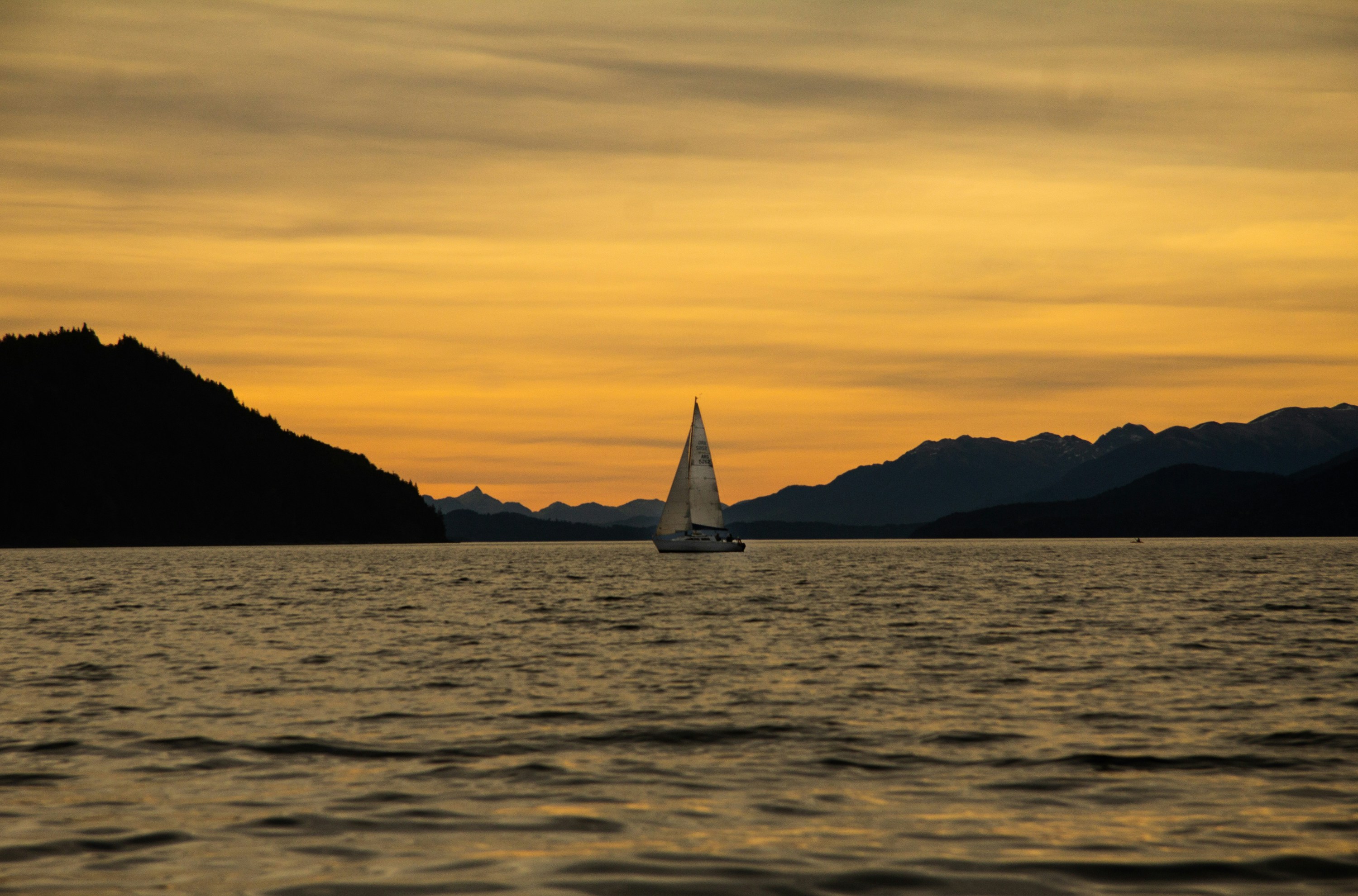 a sailboat in a body of water with mountains in the background