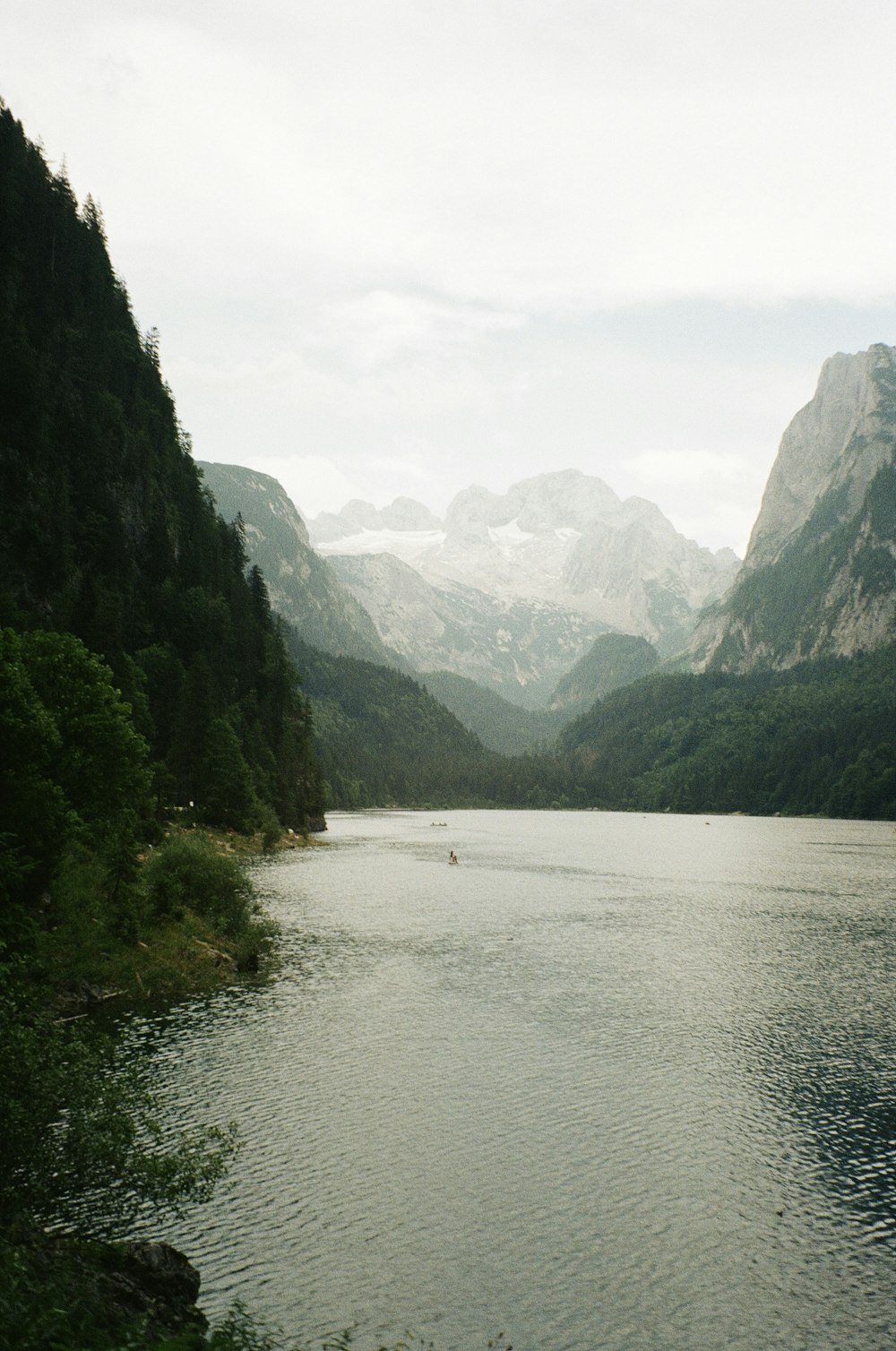 Ein Gewässer, umgeben von Bergen und Bäumen