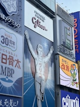A large advertisement of a runner with arms raised, wearing a white outfit. The backdrop includes additional signage in various colors and languages. The atmosphere is illustrative and commercial with visibility of surrounding billboards.