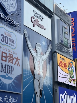 A large advertisement of a runner with arms raised, wearing a white outfit. The backdrop includes additional signage in various colors and languages. The atmosphere is illustrative and commercial with visibility of surrounding billboards.