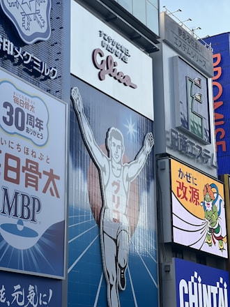 A large advertisement of a runner with arms raised, wearing a white outfit. The backdrop includes additional signage in various colors and languages. The atmosphere is illustrative and commercial with visibility of surrounding billboards.