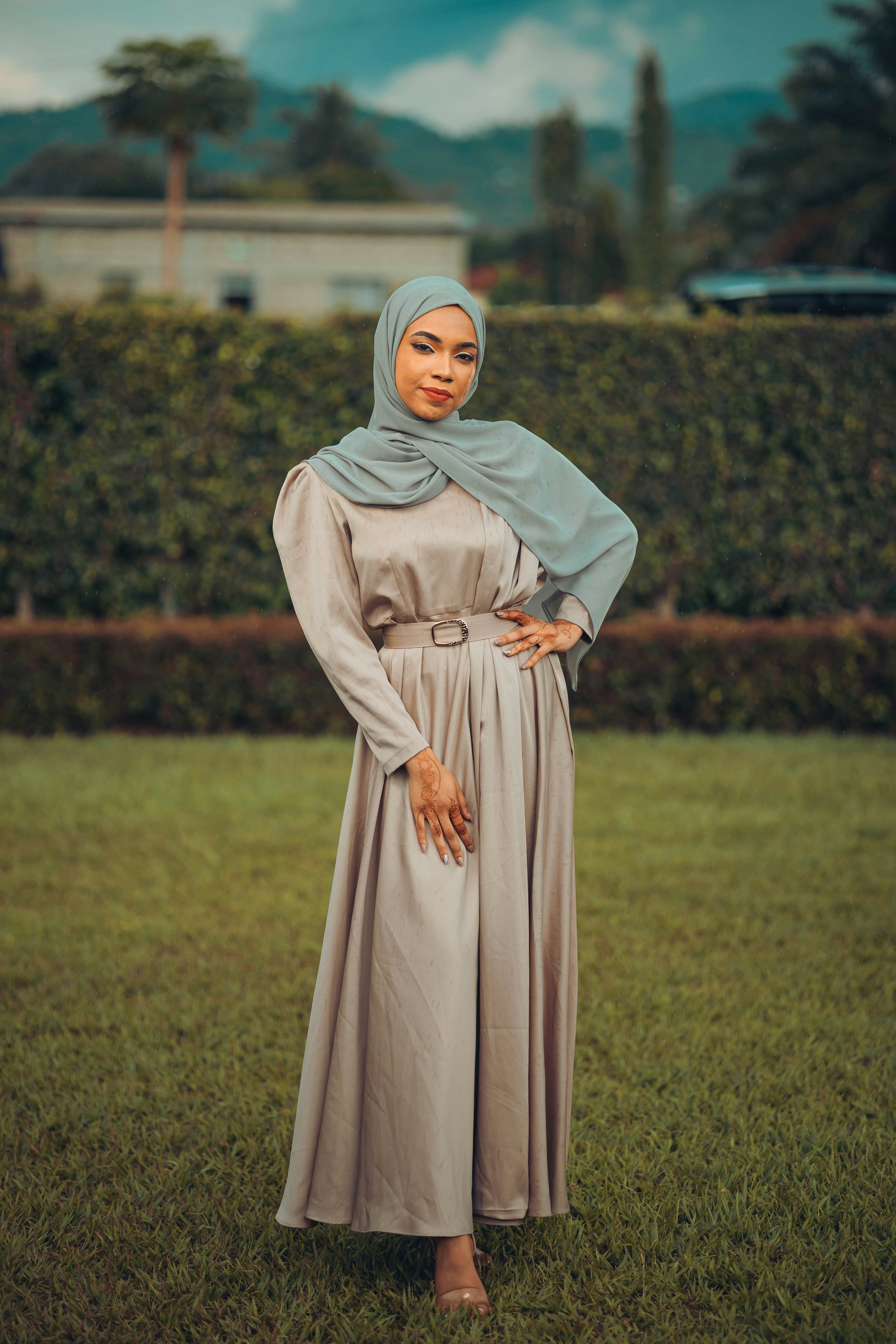 Elegant Muslim woman styling modest fashion outfit with flowing hijab and contemporary accessories in natural lighting