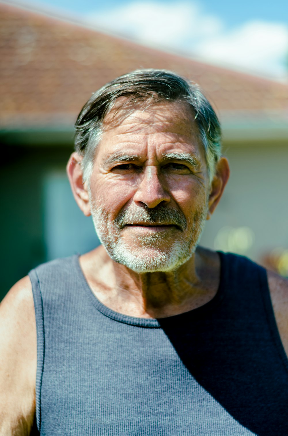 a man with a beard and a blue tank top