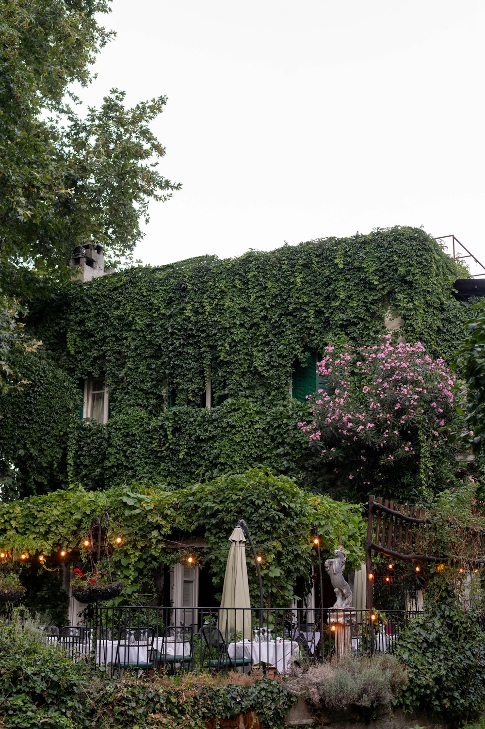 a building covered in vines with tables and umbrellas