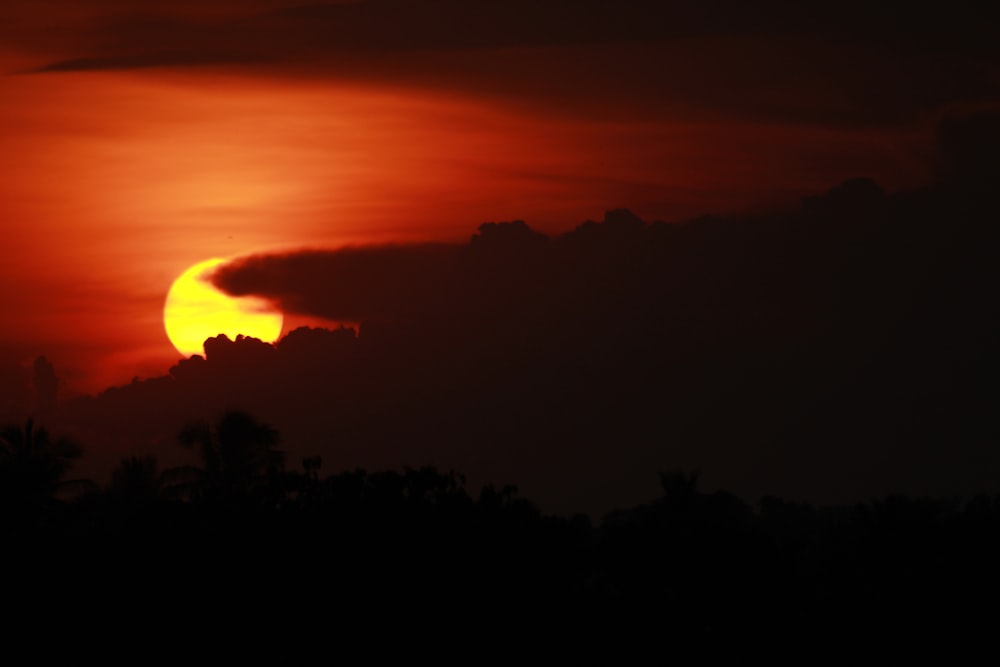 the sun is setting behind a cloud in the sky