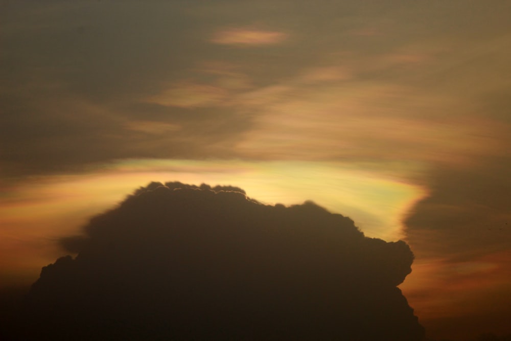 the sun is setting behind a cloud in the sky