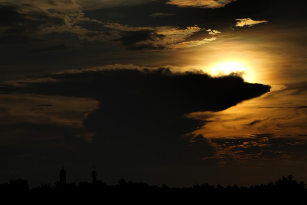 the sun is setting behind a cloud in the sky