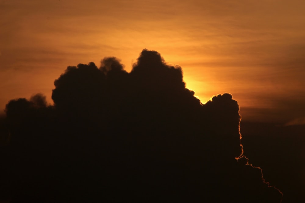 the sun is setting behind a cloud in the sky