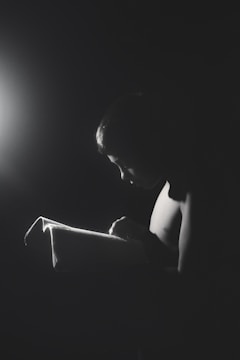 A young girl reading a book in a brightly lit classroom.