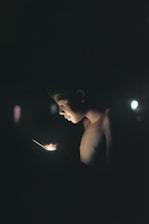 A close-up of an iPhone screen displaying the FlashGlow app interface glowing brightly in a dark room.