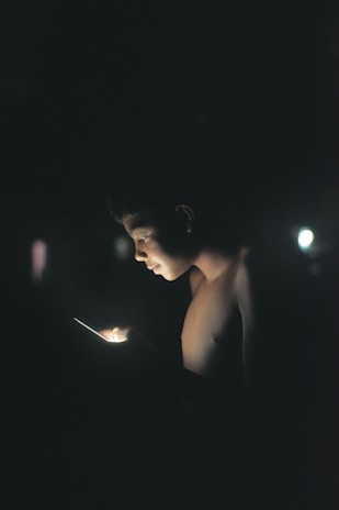 A close-up of an iPhone screen displaying the FlashGlow app interface glowing brightly in a dark room.