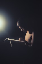 A contemplative author reading in a serene, dimly lit study.
