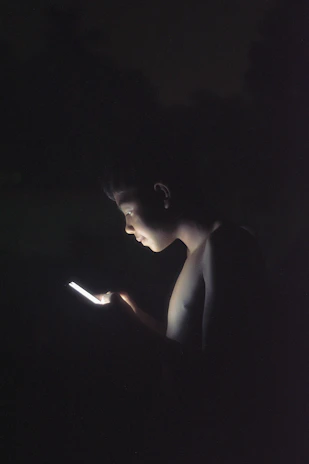 Close-up of a gamer’s focused face illuminated by vibrant screens showing performance metrics and social media feeds.