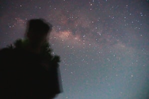 Silhouette of a figure standing under a swirling, starry night sky.