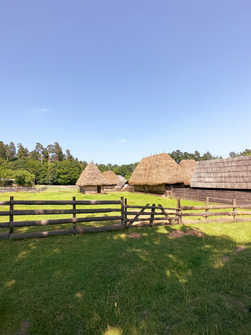 a wooden fence in front of a grassy field