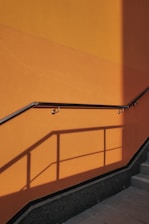 a man walking down a flight of stairs next to a yellow wall