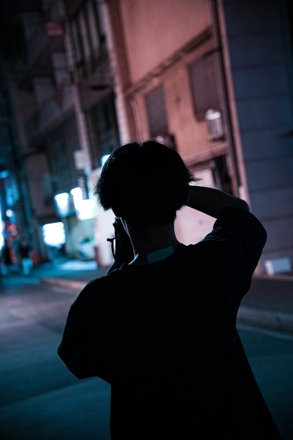 a person standing on the side of a street talking on a cell phone