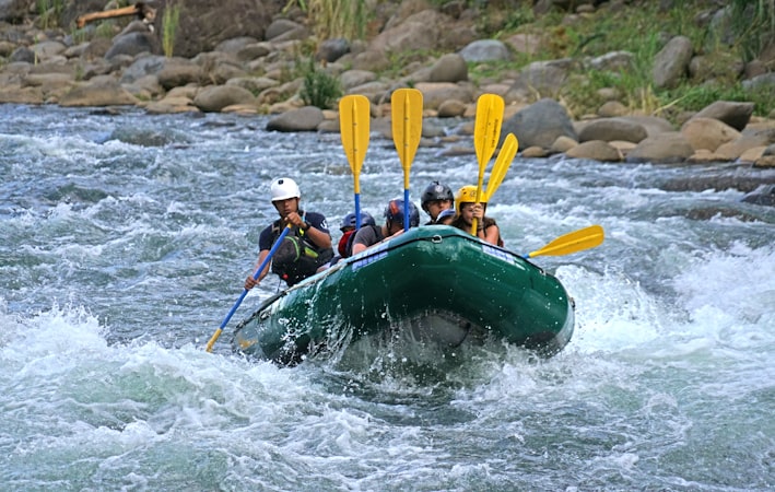 Peserta arung jeram memakai helm dan pelampung keselamatan di perahu karet