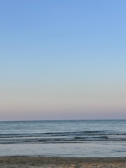 A serene beach scene with gentle waves and a pastel sky.