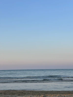 A serene beach scene with gentle waves under a pastel sky.