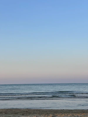 A serene beach scene with soft pastel skies and gentle waves lapping the shore.
