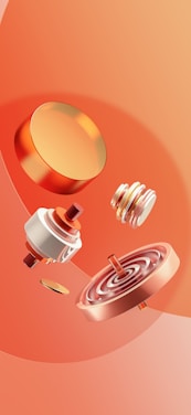 Several metallic and circular objects with shiny surfaces are arranged against a vibrant orange backdrop. The objects appear to be components of a mechanical or electronic device, featuring gears, coils, and flat circular parts.