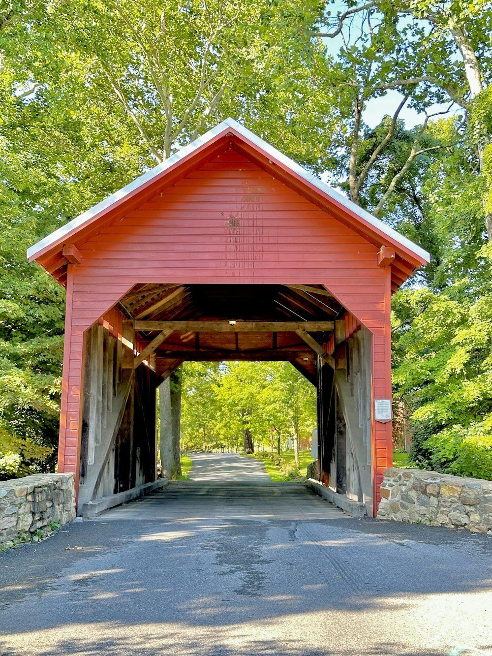 a red covered bridge in the middle of a forest