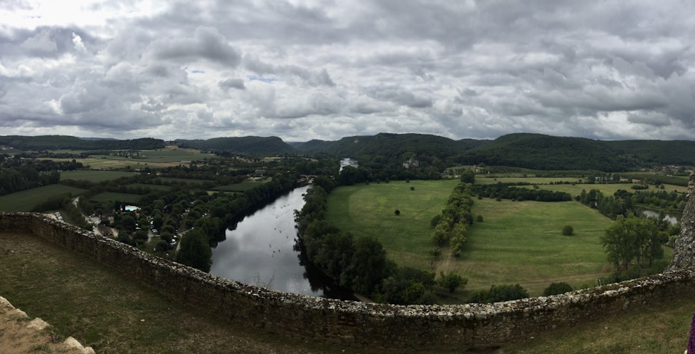 a woman standing on top of a stone wall next to a river